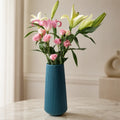 Florero decorativo azul de diseño estriado con flores rosadas para sala o comedor