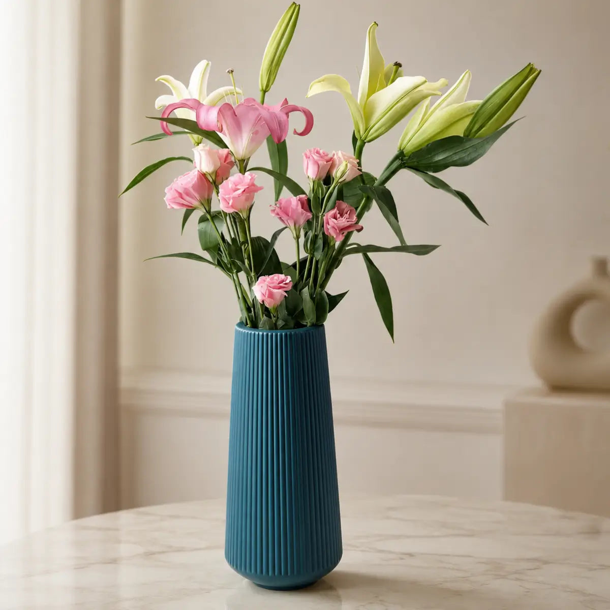 Florero decorativo azul de diseño estriado con flores rosadas para sala o comedor