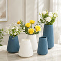 Floreros decorativos estriados en azul y blanco con diferentes tamaños y arreglos florales